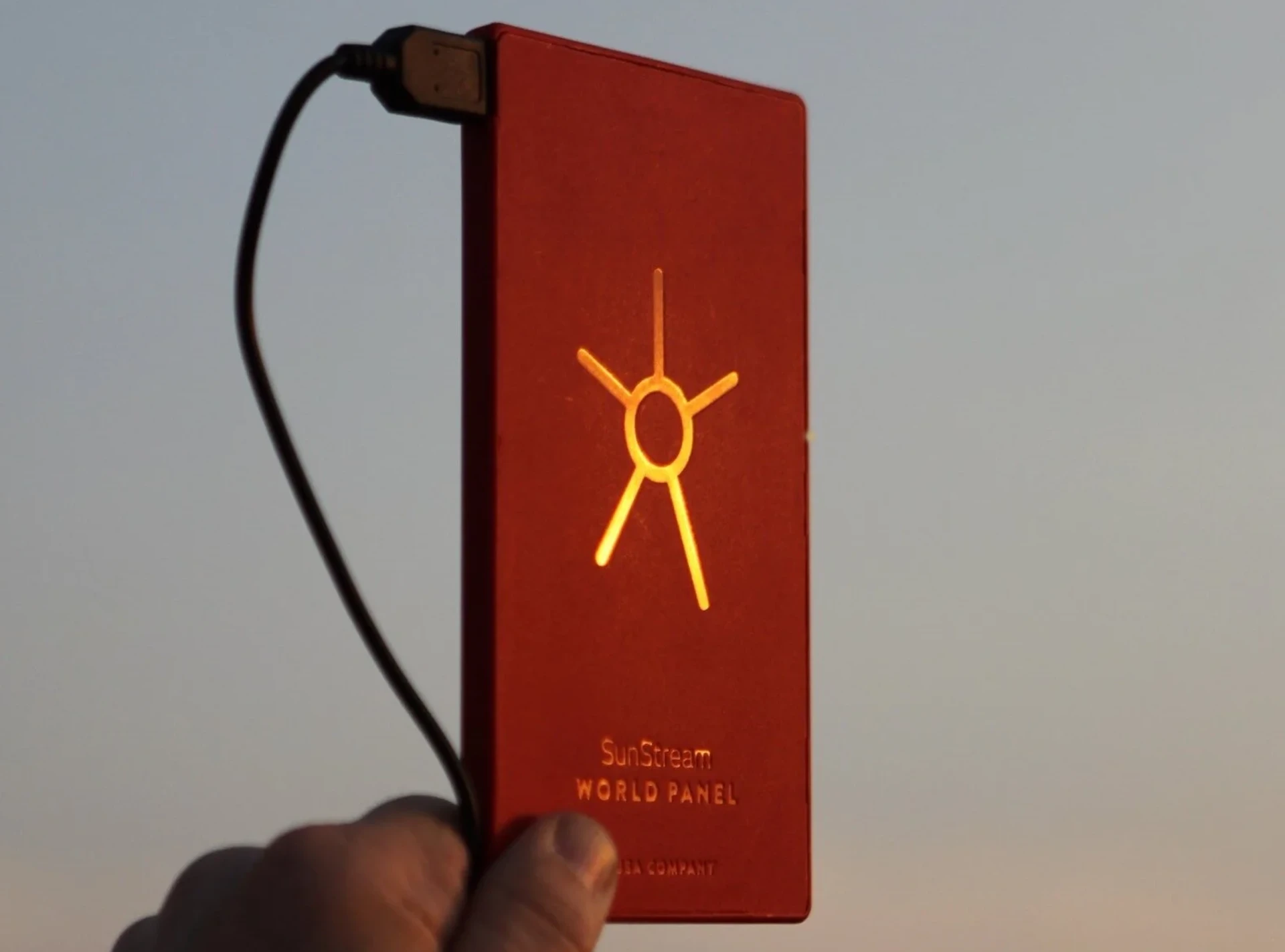 SunStream solar charging device held against a sunset